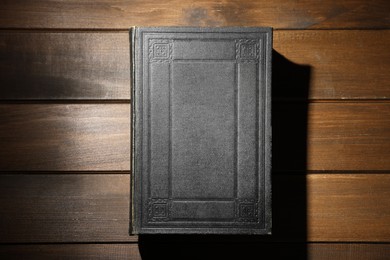 Photo of Closed Bible on wooden table, top view