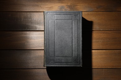 Photo of Closed Bible on wooden table, top view