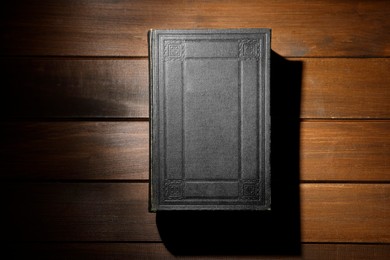 Photo of Closed Bible on wooden table, top view