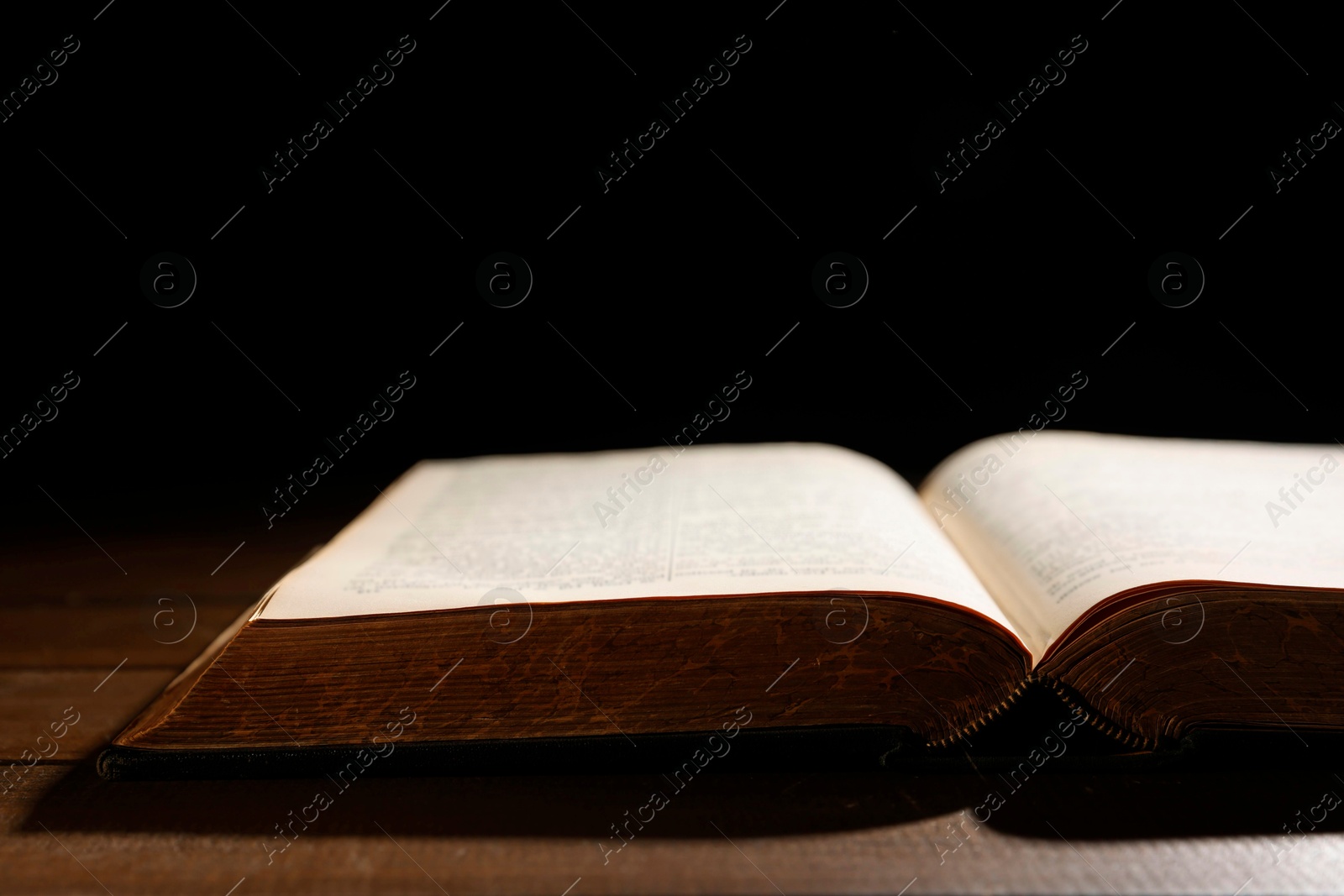 Photo of Open Bible on wooden table, closeup. Christian faith