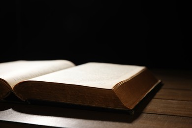 Photo of Open Bible on wooden table, closeup. Christian faith