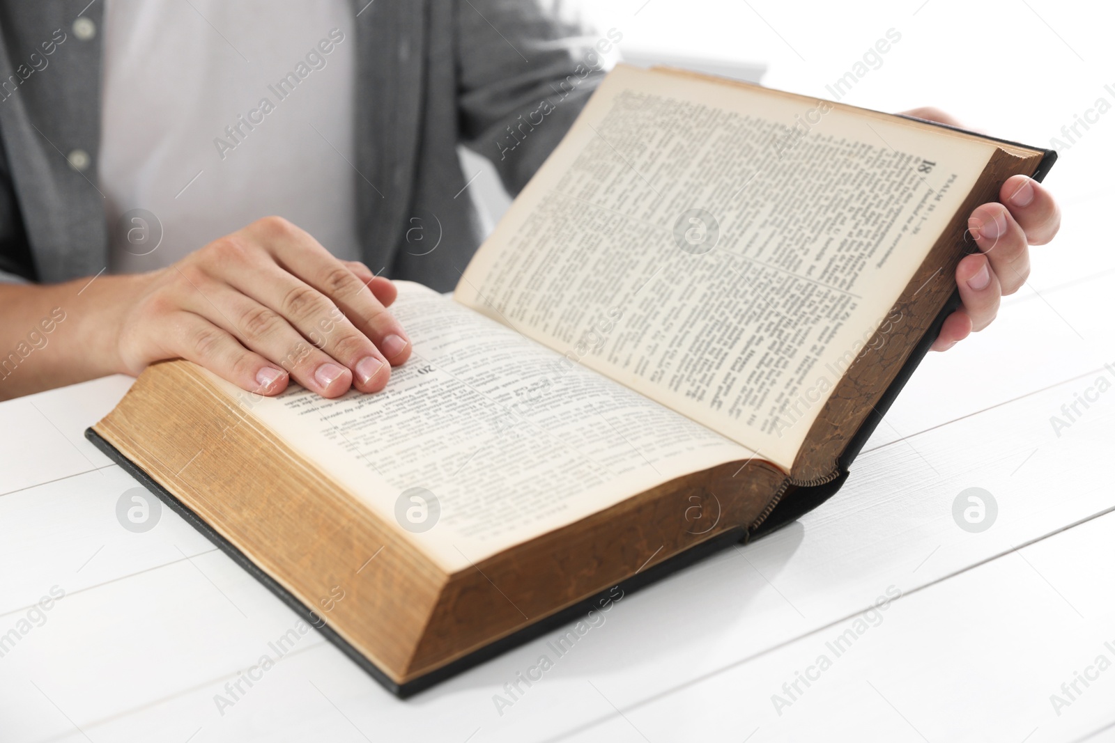 Photo of Man with Bible at white wooden table, closeup