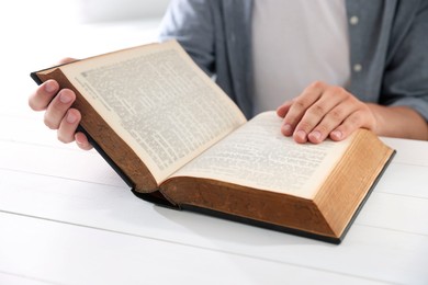 Photo of Man with Bible at white wooden table, closeup