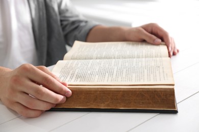 Photo of Man with Bible at white wooden table, closeup