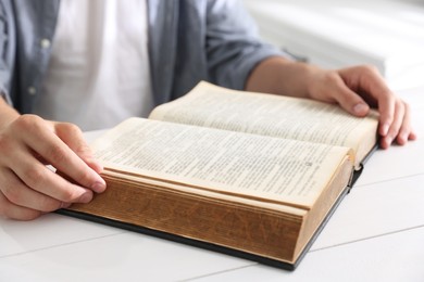 Photo of Man with Bible at white wooden table, closeup