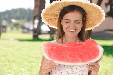 Happy woman with slice of juicy watermelon outdoors, space for text