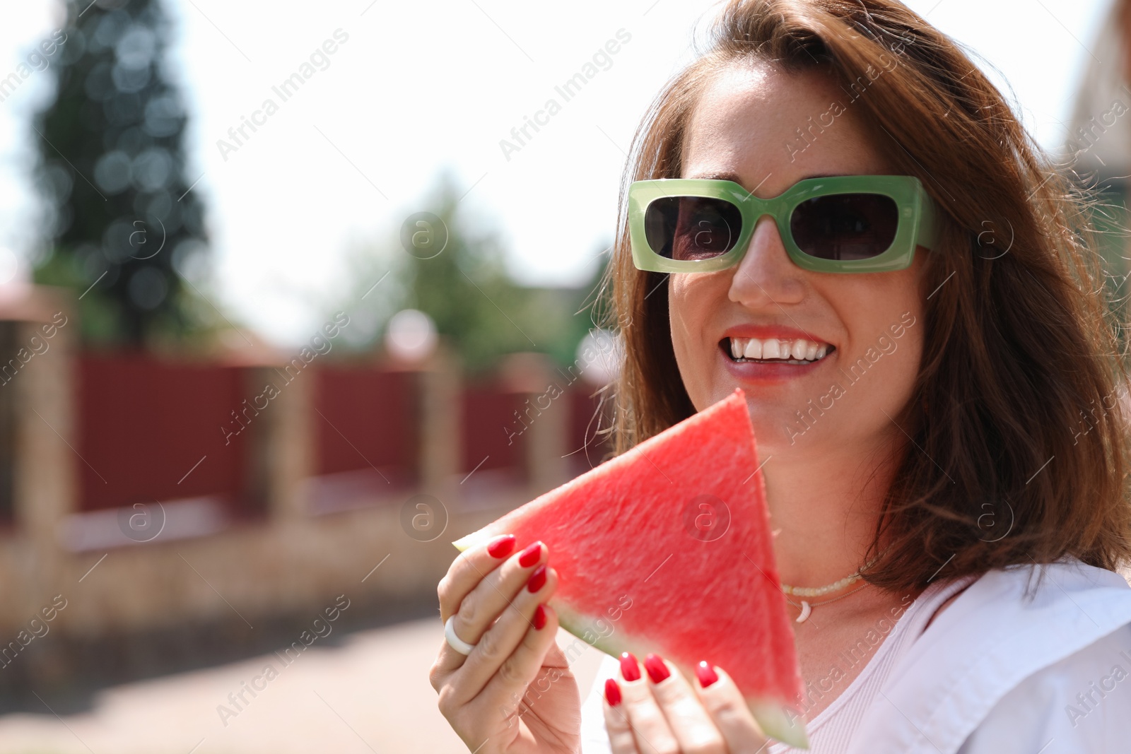 Photo of Happy woman with slice of juicy watermelon outdoors, space for text