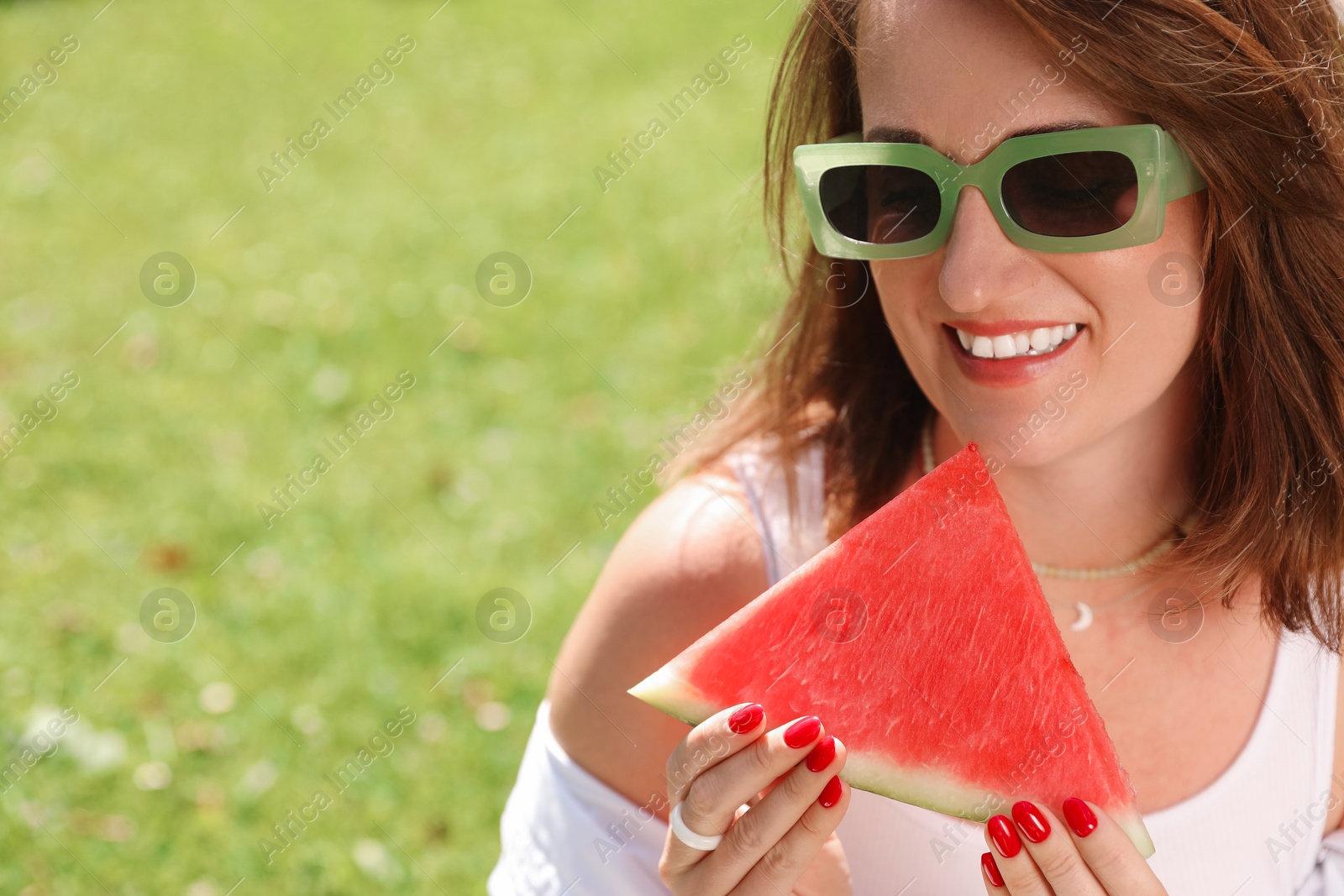 Photo of Happy woman with slice of juicy watermelon outdoors, space for text