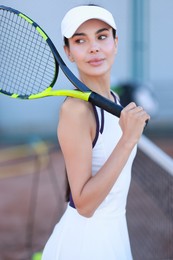 Beautiful woman with tennis racket on court