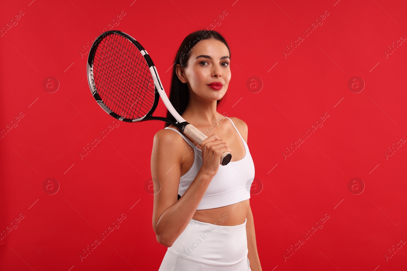 Photo of Beautiful young woman with tennis racket on red background