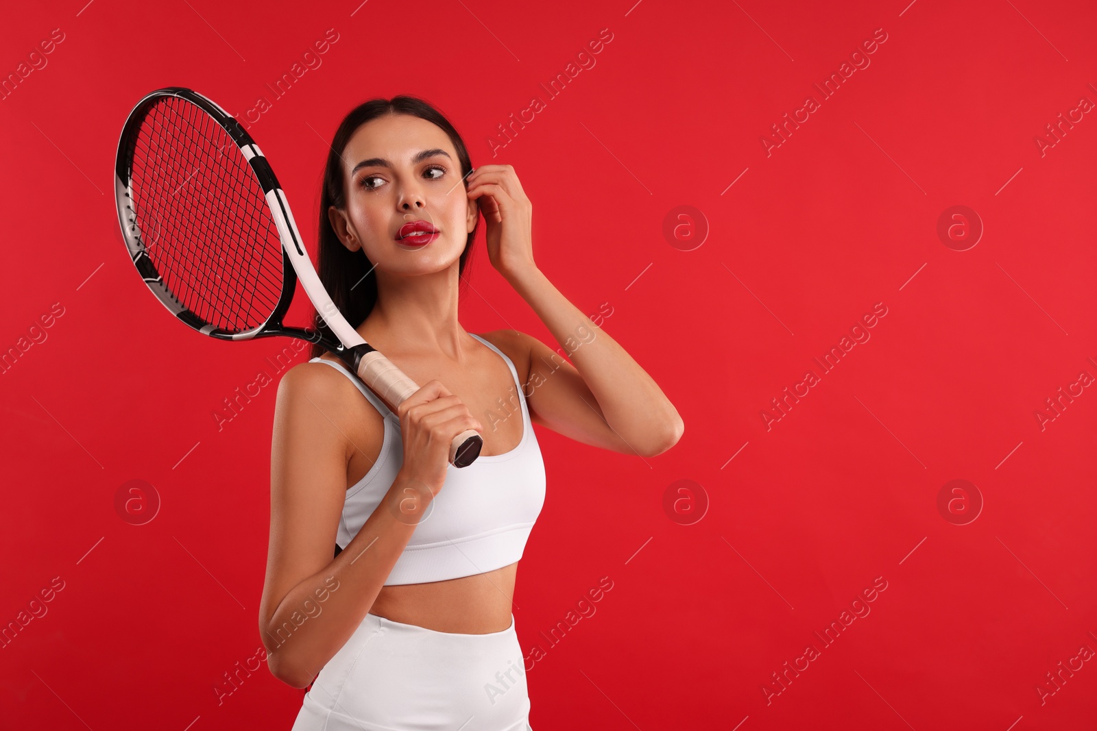 Photo of Beautiful young woman with tennis racket on red background, space for text