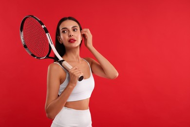 Beautiful young woman with tennis racket on red background, space for text