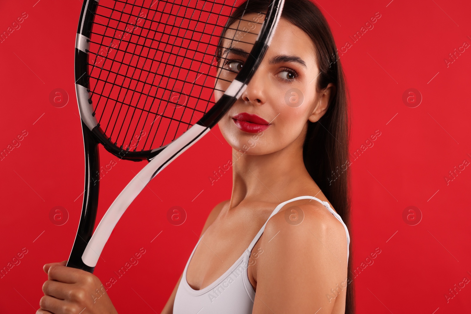 Photo of Beautiful young woman with tennis racket on red background