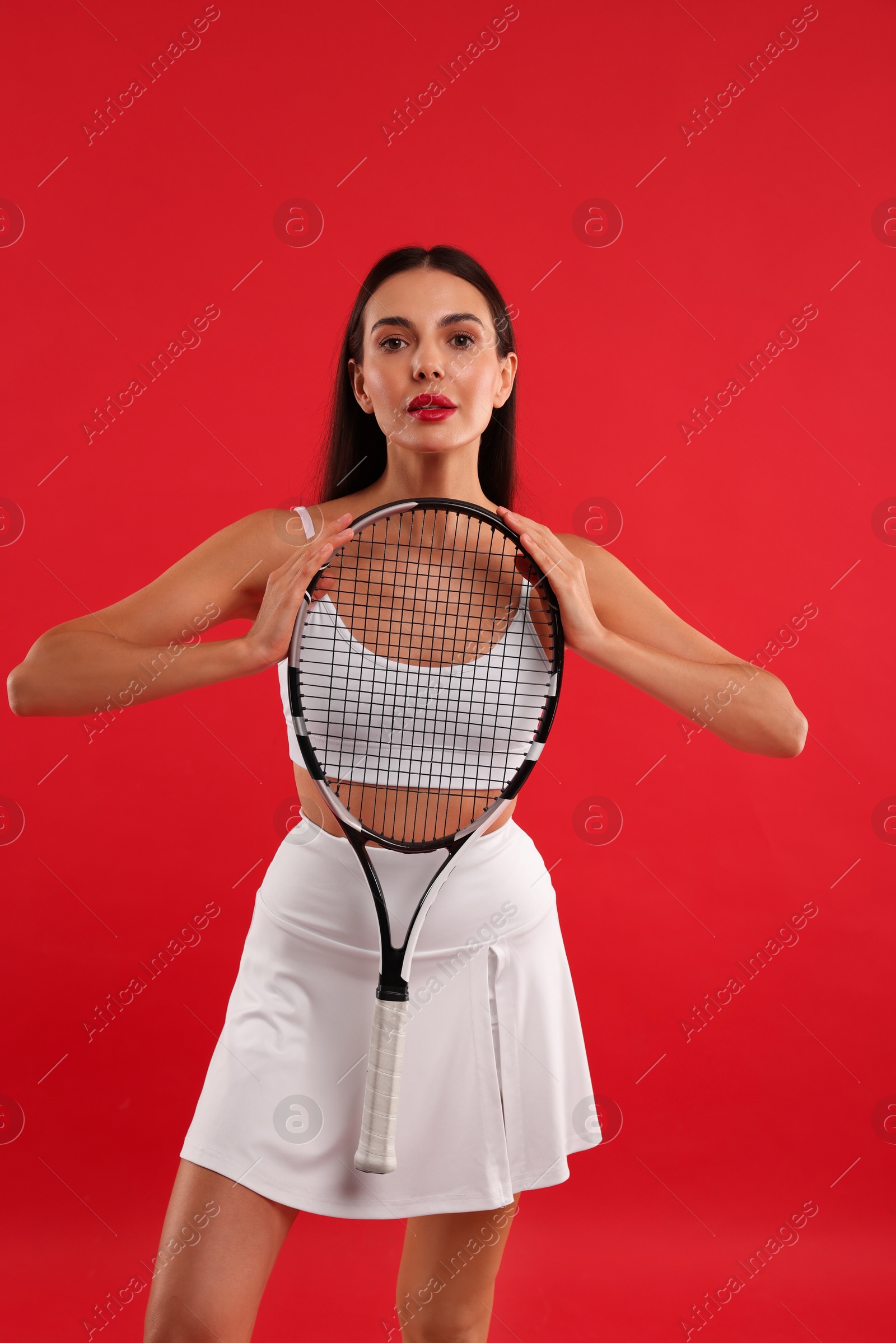 Photo of Beautiful young woman with tennis racket on red background