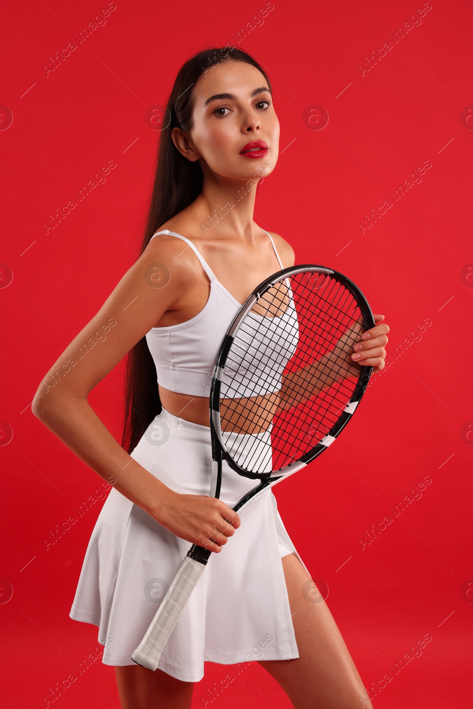 Photo of Beautiful young woman with tennis racket on red background