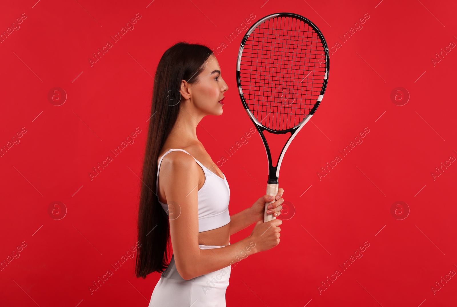 Photo of Beautiful young woman with tennis racket on red background