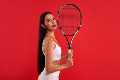 Beautiful young woman with tennis racket on red background