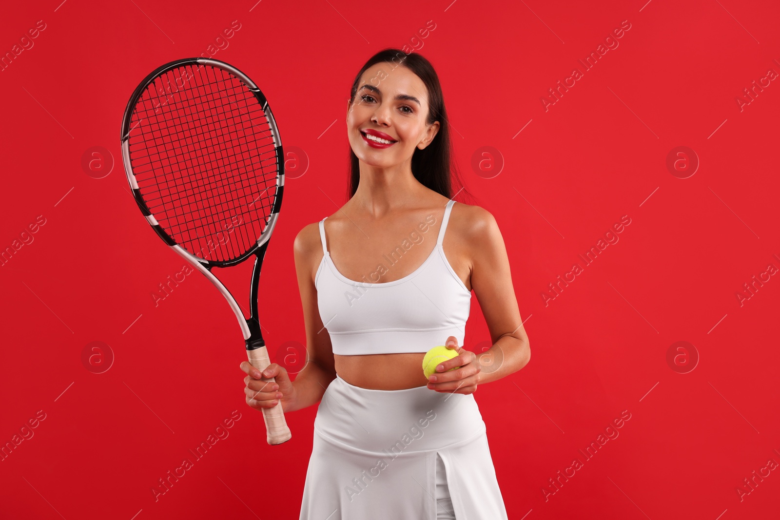 Photo of Happy tennis player with racket and ball on red background