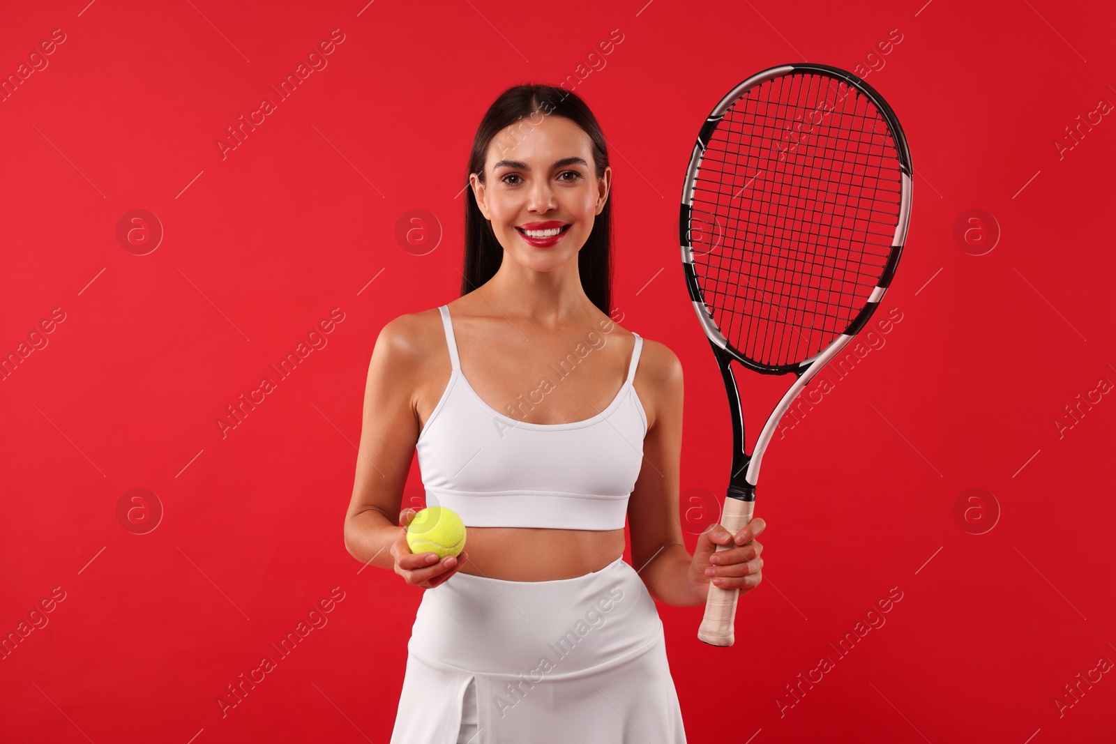 Photo of Happy tennis player with racket and ball on red background