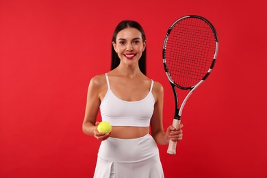 Photo of Happy tennis player with racket and ball on red background