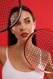 Photo of Portrait of beautiful young woman with tennis rackets on red background