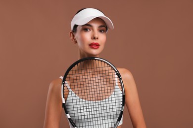 Photo of Beautiful young woman with tennis racket on brown background