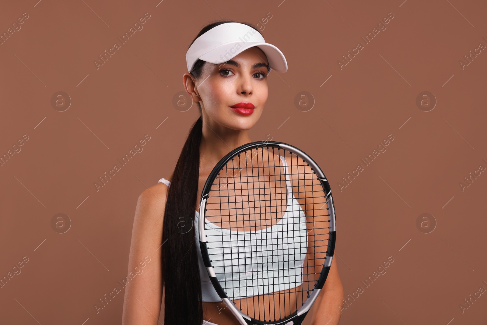 Photo of Beautiful young woman with tennis racket on brown background