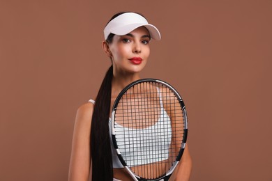 Beautiful young woman with tennis racket on brown background