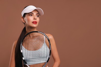 Photo of Beautiful young woman with tennis racket on brown background, space for text