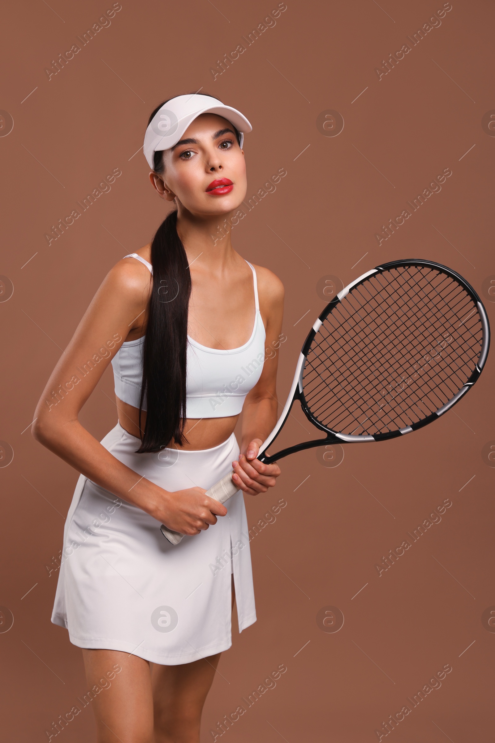 Photo of Beautiful young woman with tennis racket on brown background