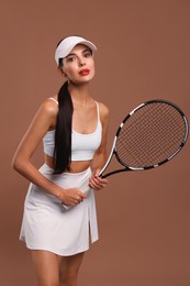 Beautiful young woman with tennis racket on brown background