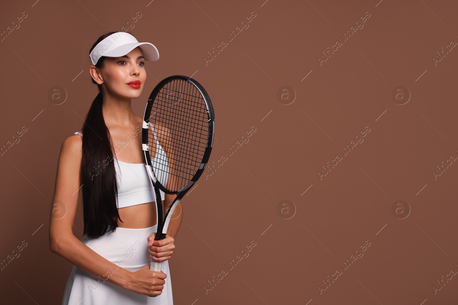 Photo of Beautiful young woman with tennis racket on brown background, space for text