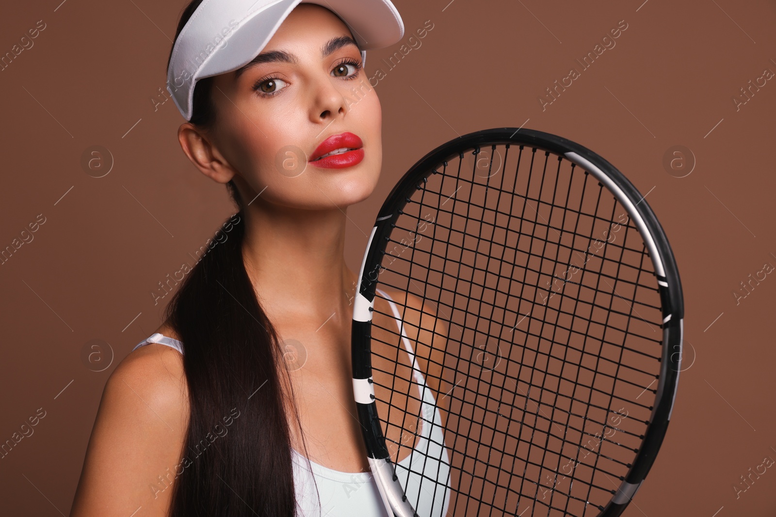 Photo of Beautiful young woman with tennis racket on brown background