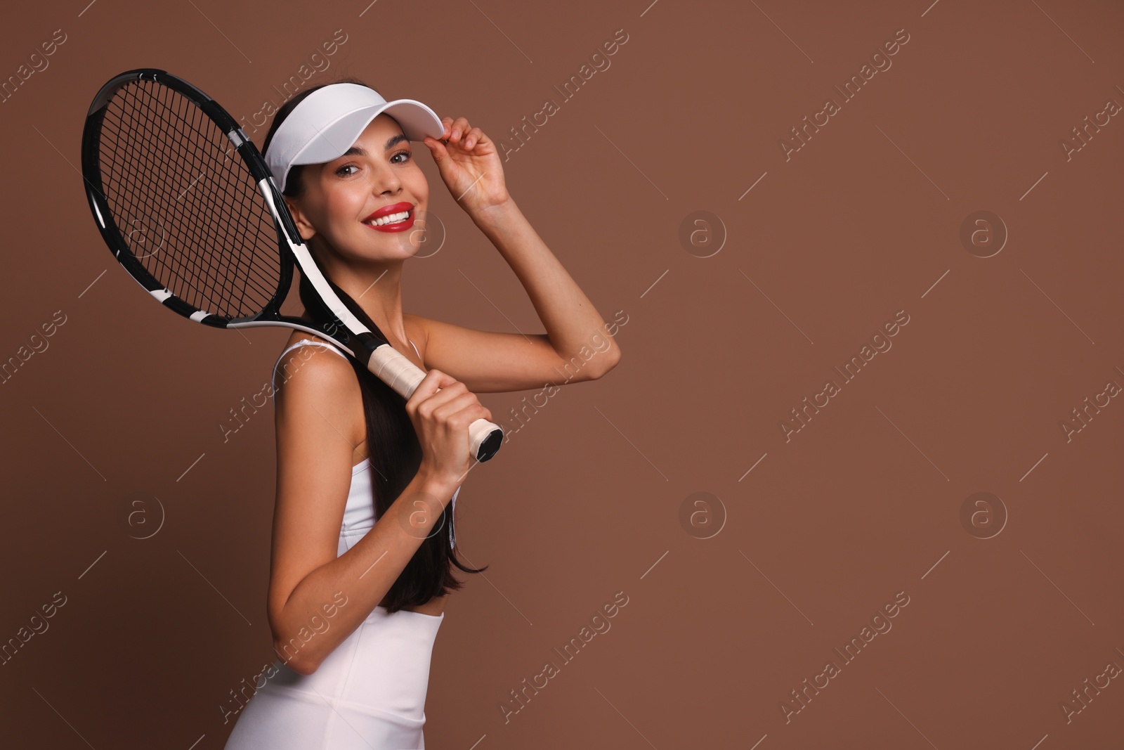 Photo of Beautiful young woman with tennis racket on brown background, space for text