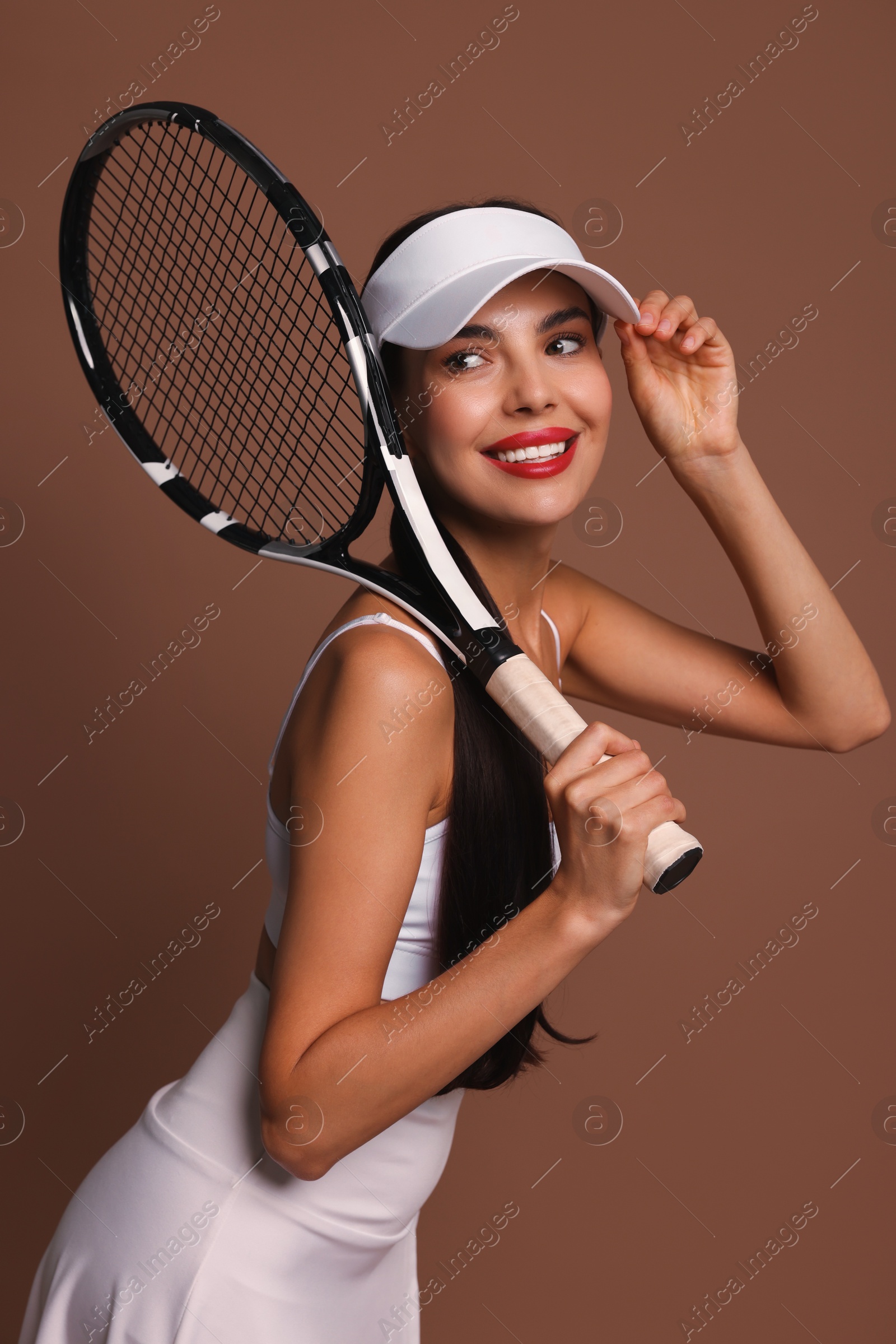 Photo of Beautiful young woman with tennis racket on brown background