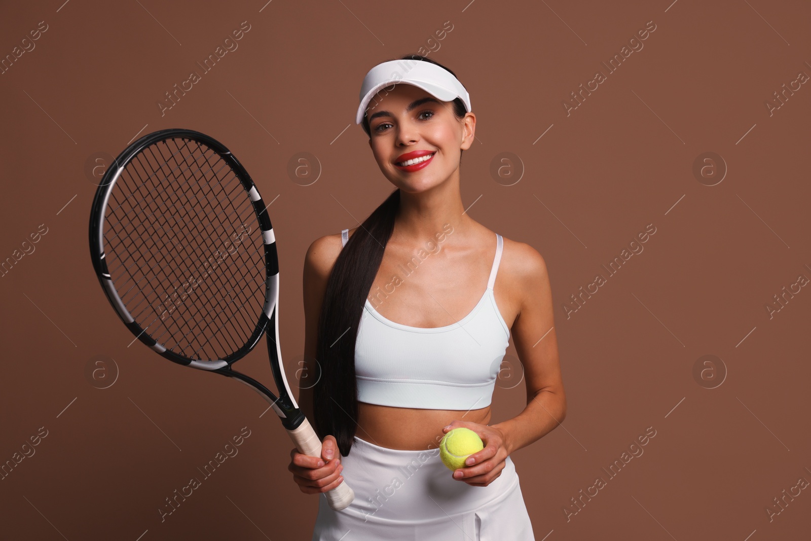 Photo of Happy tennis player with racket and ball on brown background