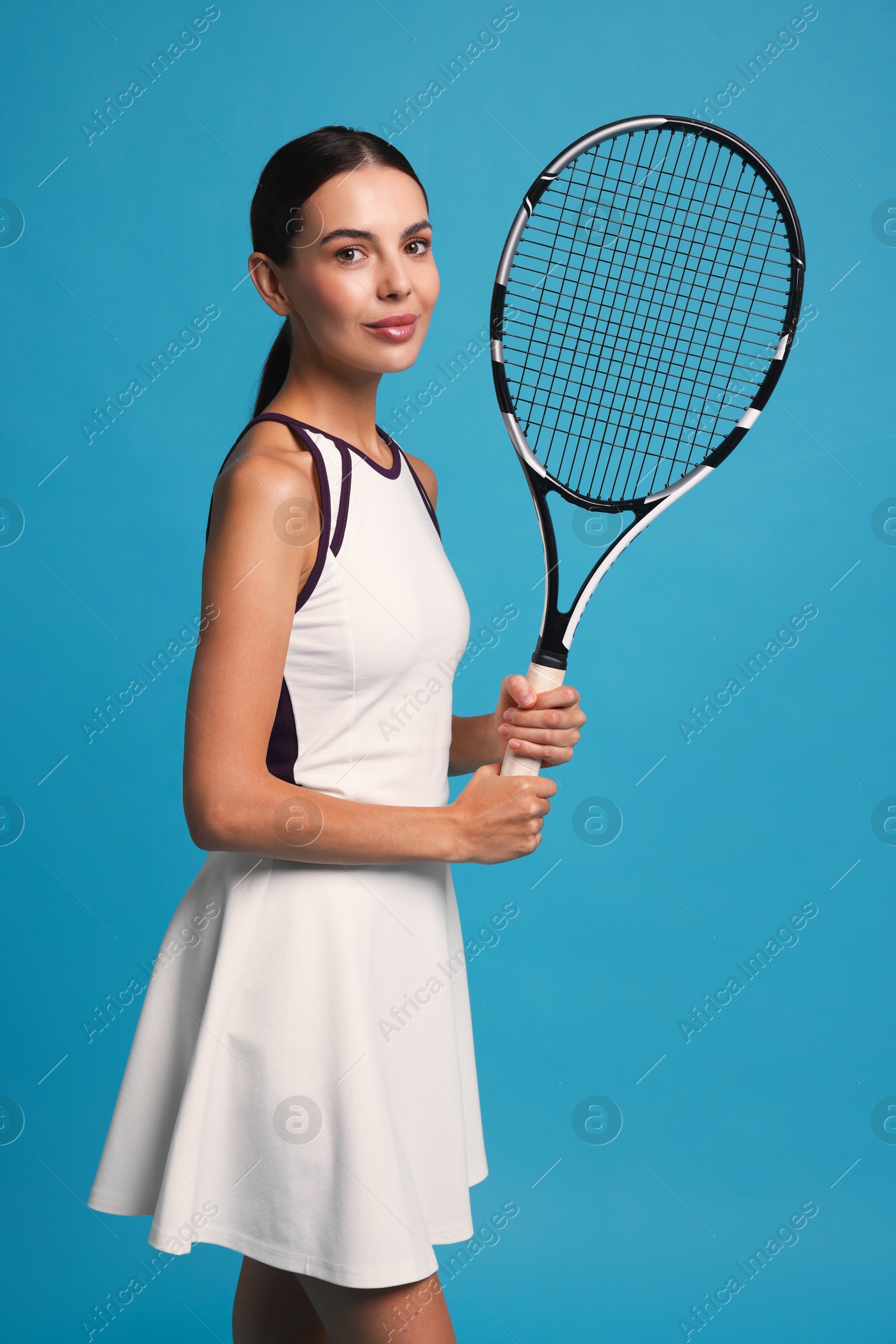 Photo of Beautiful young woman with tennis racket on light blue background