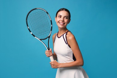 Beautiful young woman with tennis racket on light blue background