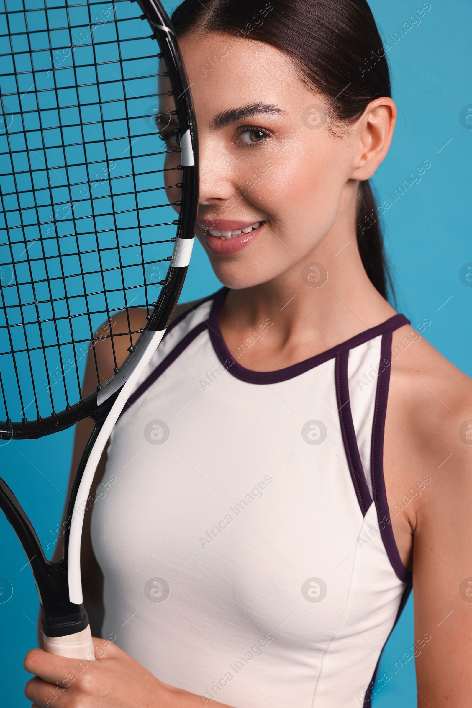 Photo of Beautiful young woman with tennis racket on light blue background