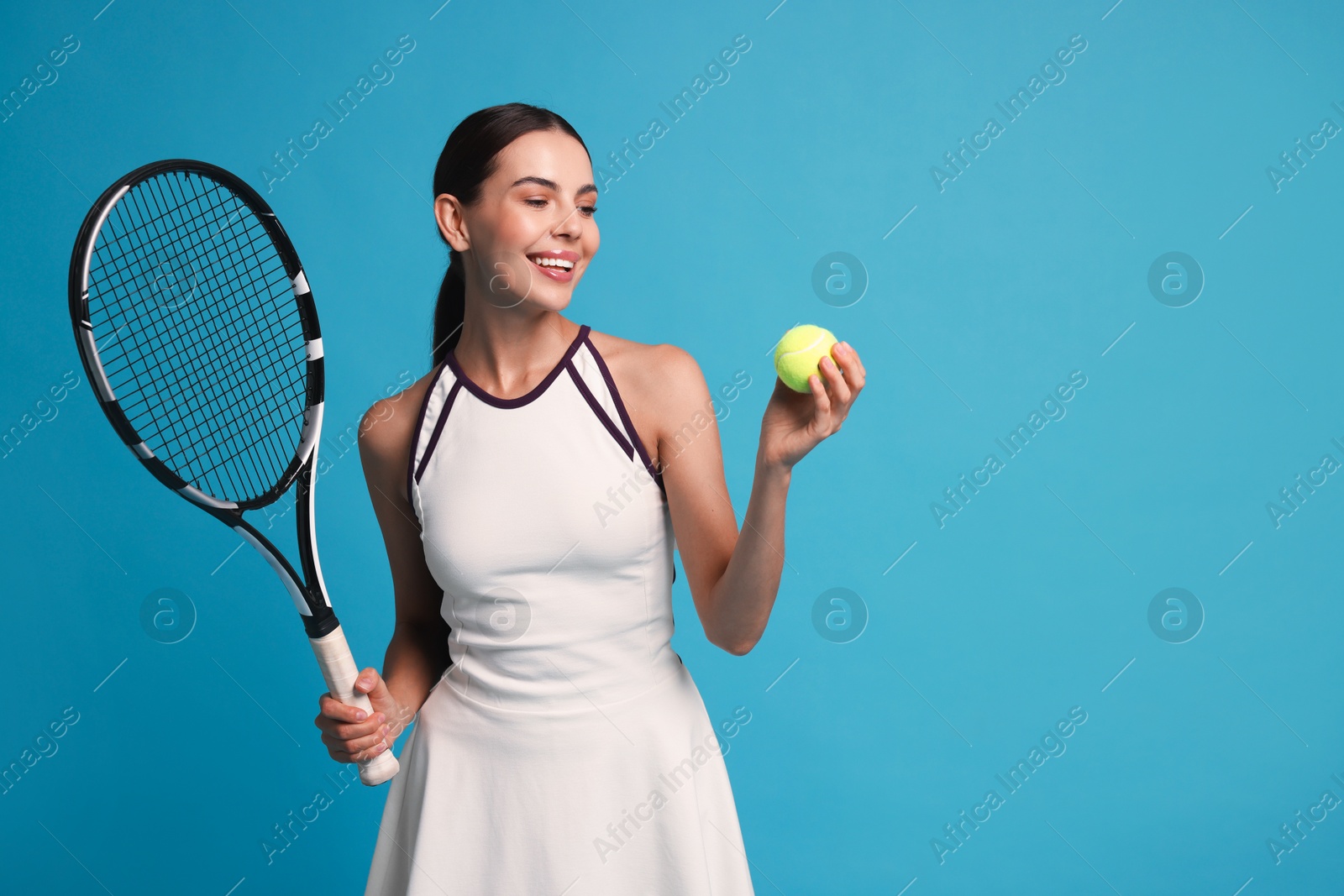 Photo of Happy tennis player with racket and ball on light blue background, space for text