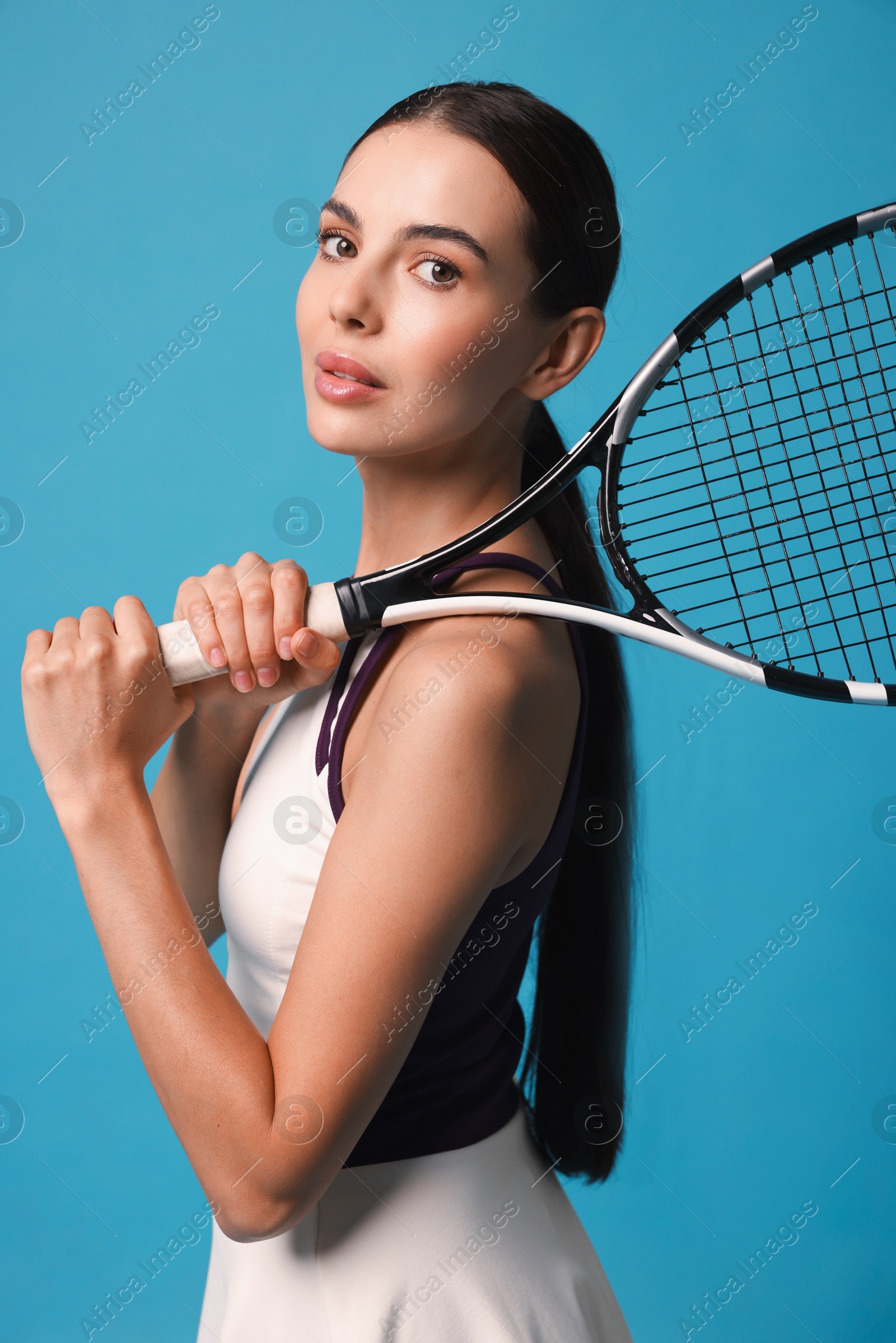 Photo of Beautiful young woman with tennis racket on light blue background