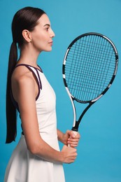 Beautiful young woman with tennis racket on light blue background