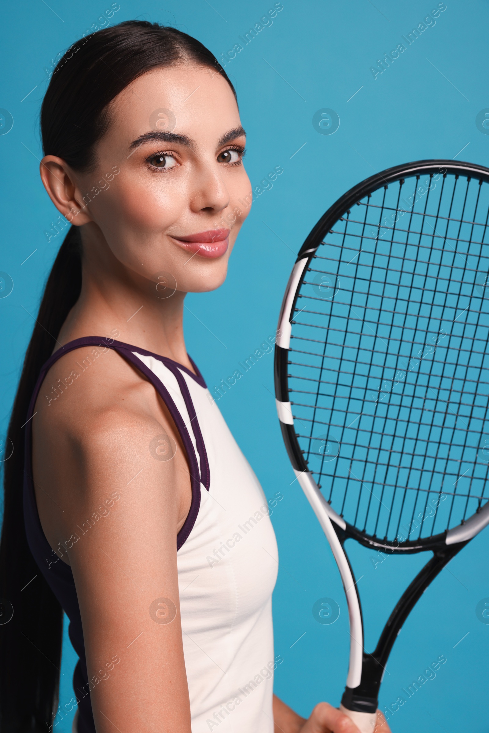 Photo of Beautiful young woman with tennis racket on light blue background