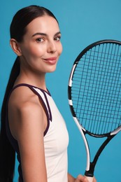 Beautiful young woman with tennis racket on light blue background