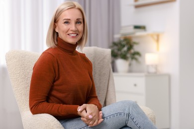 Portrait of smiling middle aged woman on armchair at home