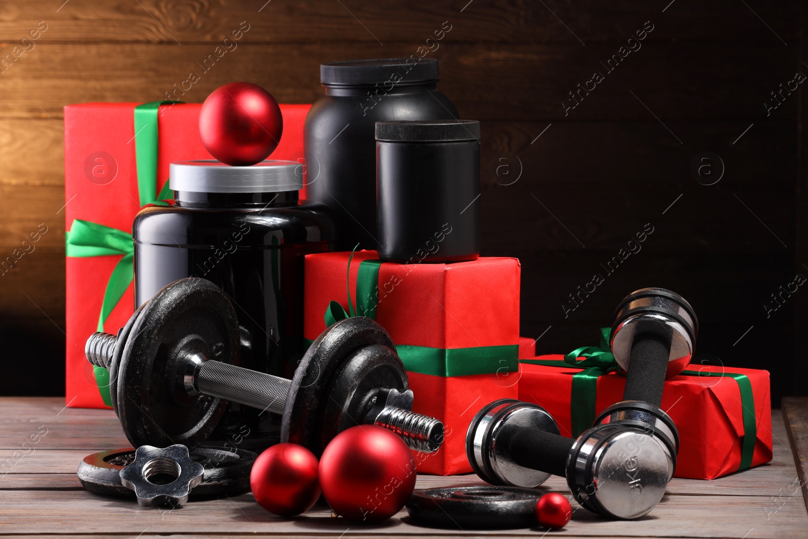 Photo of Dumbbells, containers with supplement and Christmas decor on wooden table