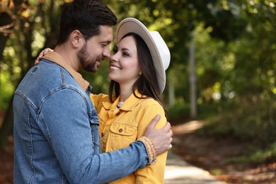 Photo of Beautiful couple hugging in park on autumn day, space for text