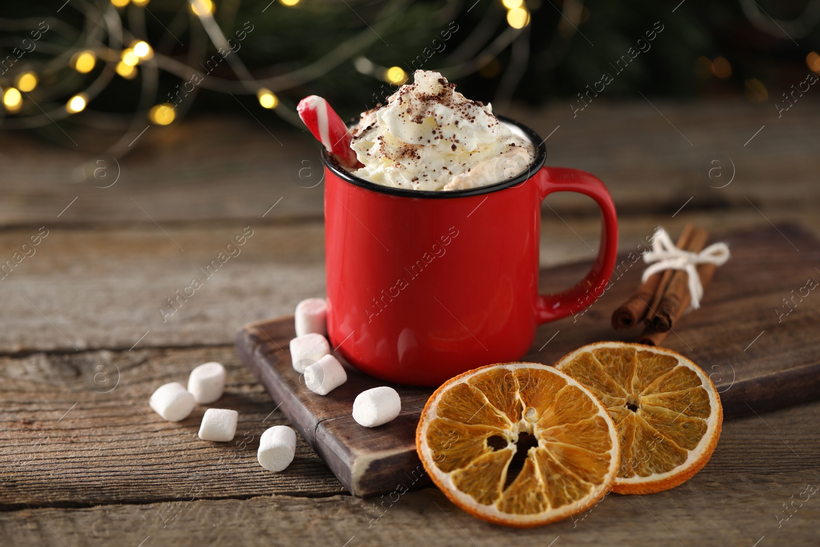 Photo of Tasty hot cocoa drink with whipped cream in mug, marshmallows and spices on wooden table