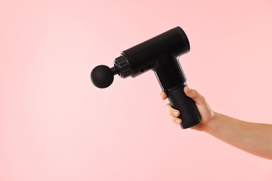 Photo of Woman holding percussive massager on pink background, closeup