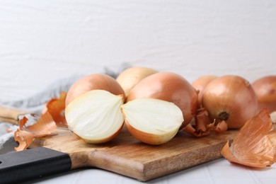 Photo of Fresh onions with peels on white tiled table, closeup